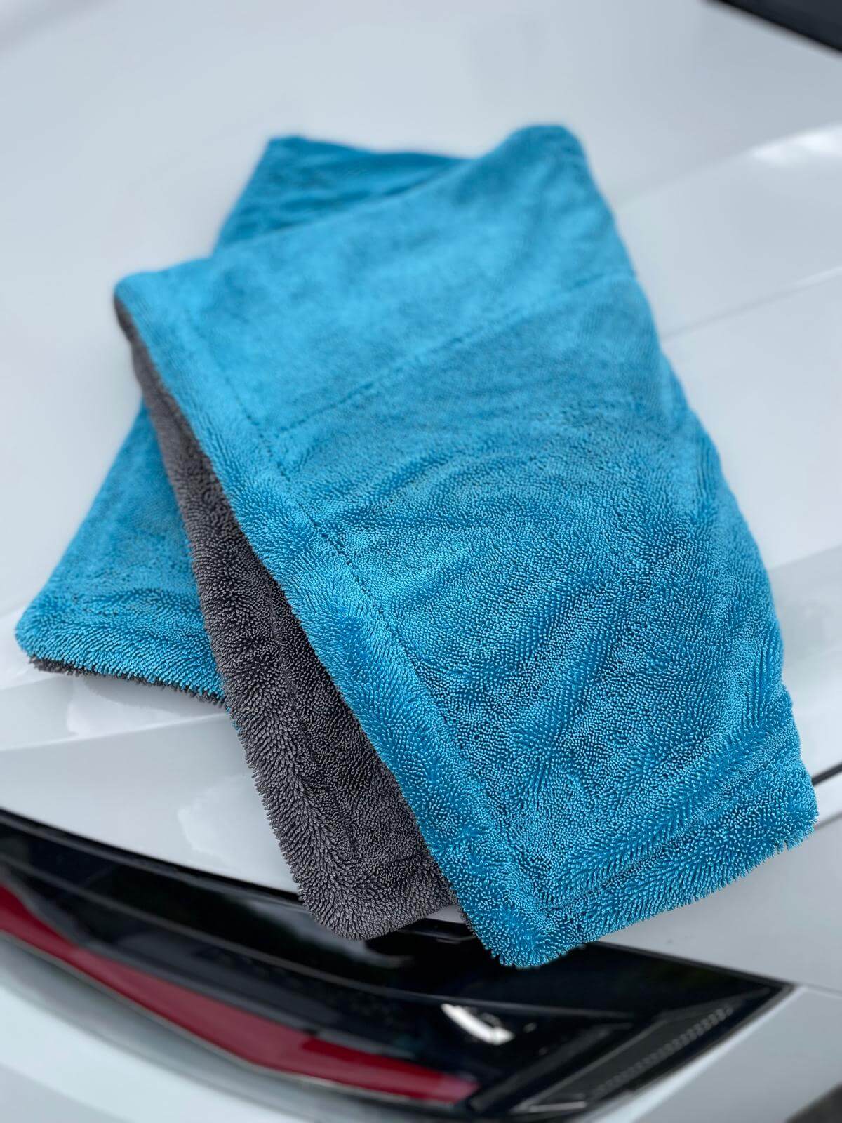 Erixen Mikrofaser Trockentuch in Blau und Grau auf einem glänzenden Auto, sanft und saugstark.