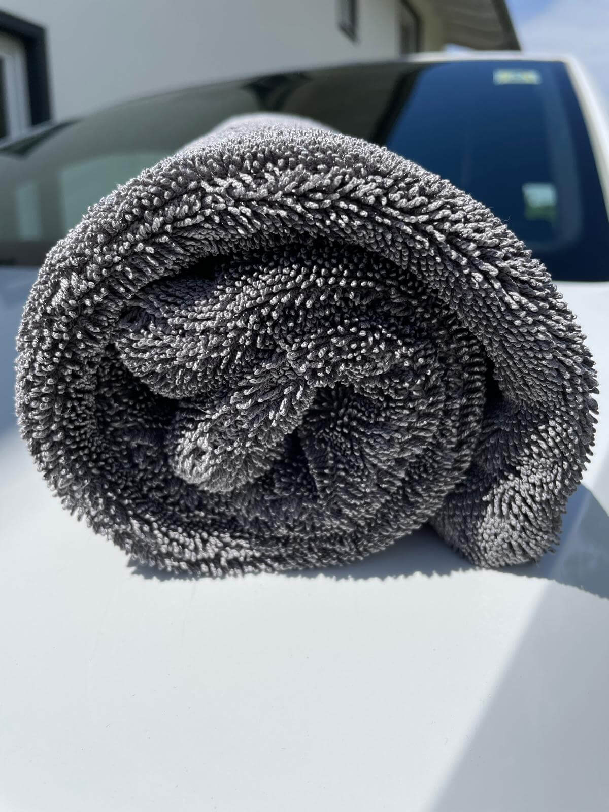Erixen Mikrofaser Trockentuch in Grau, 1600 GSM, gerollt auf einem Auto für streifenfreies Trocknen.