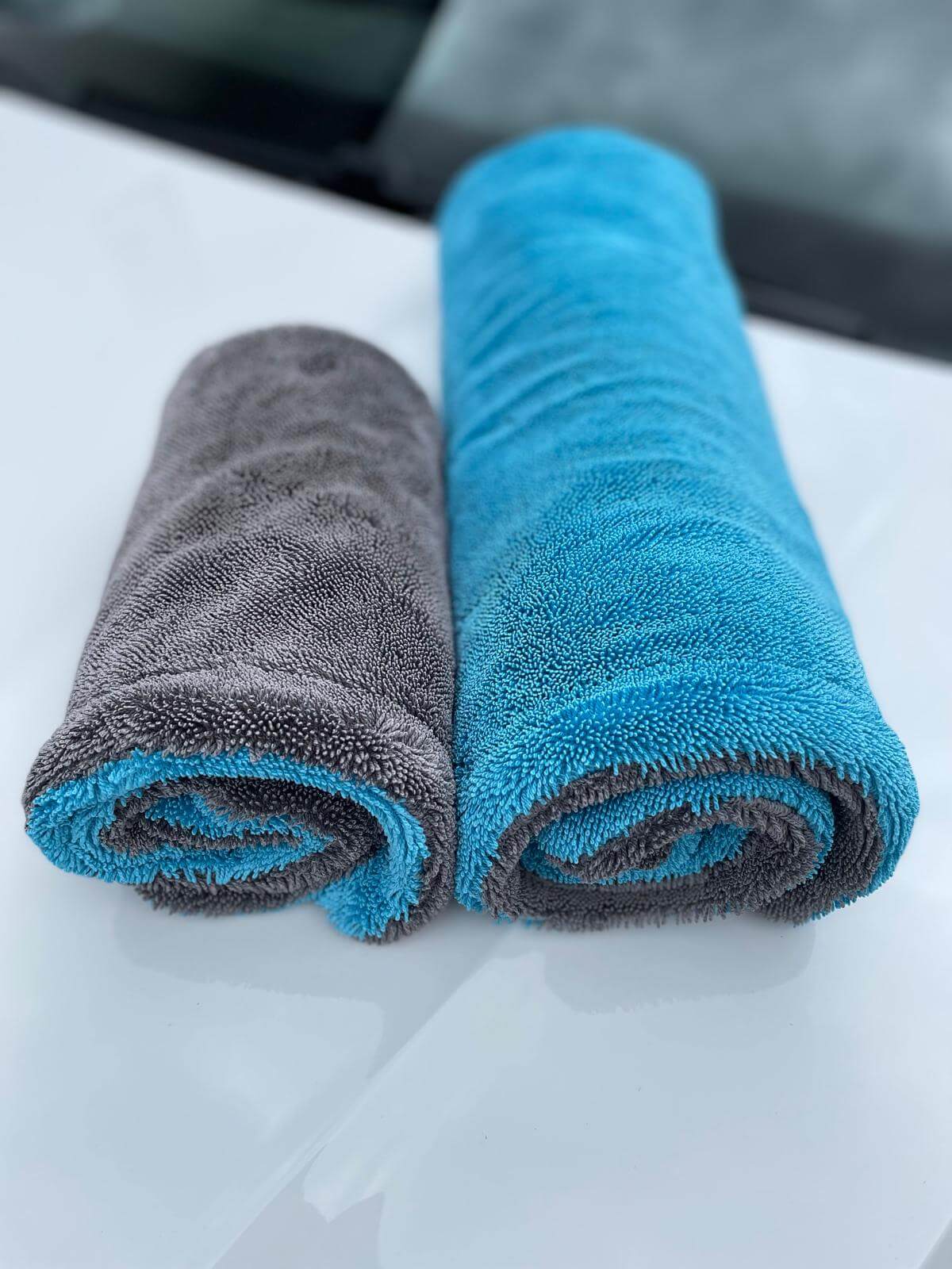 Rolled Erixen Mikrofaser Trockentuch in gray and blue, showcasing two sizes for optimal drying.